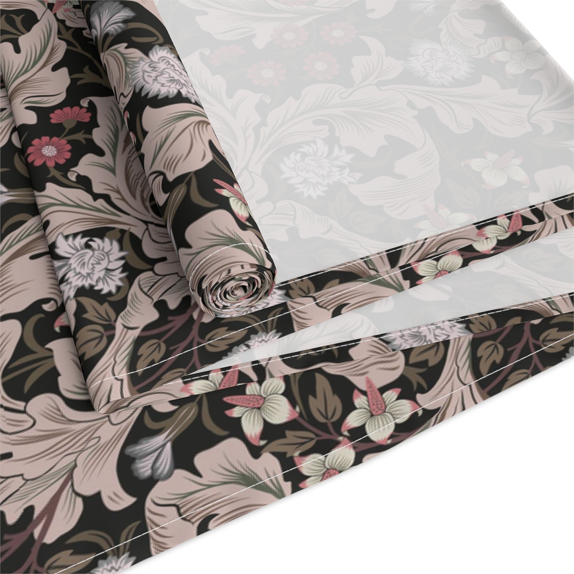 A table runner with a William Morris & Co design laid out on a dining table, flanked by plates and a vase with flowers, set for a meal.