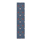 A William Morris & Co table runner with a floral pattern  called Medway in shades of red and blue, displayed on a dining table.