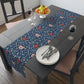 A William Morris & Co table runner with a floral pattern  called Medway in shades of red and blue, displayed on a dining table.