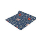 A William Morris & Co table runner with a floral pattern  called Medway in shades of red and blue, displayed on a dining table.