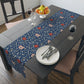 A William Morris & Co table runner with a floral pattern  called Medway in shades of red and blue, displayed on a dining table.