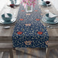 A William Morris & Co table runner with a floral pattern  called Medway in shades of red and blue, displayed on a dining table.