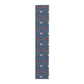 A William Morris & Co table runner with a floral pattern  called Medway in shades of red and blue, displayed on a dining table.