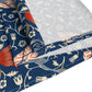 A William Morris & Co table runner with a floral pattern  called Medway in shades of red and blue, displayed on a dining table.