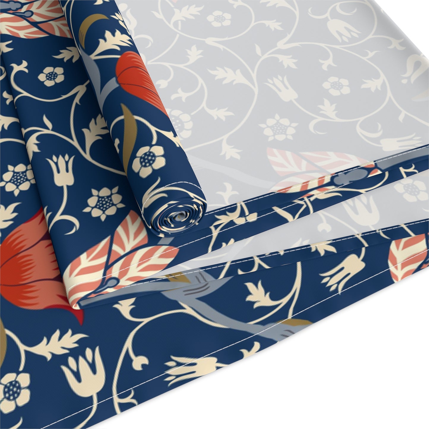 A William Morris & Co table runner with a floral pattern  called Medway in shades of red and blue, displayed on a dining table.