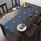 A William Morris & Co table runner with a floral pattern  called Medway in shades of red and blue, displayed on a dining table.
