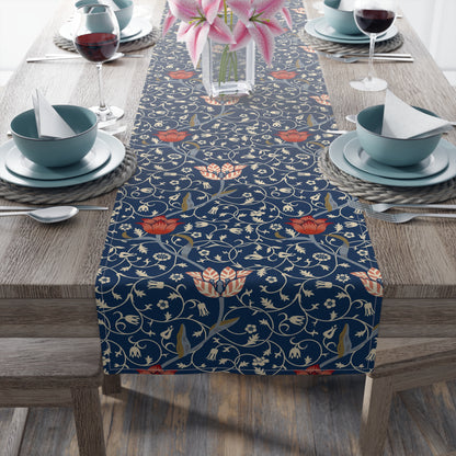 A table runner with a floral pattern in shades of red and blue, displayed on a dining table.
