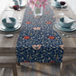A table runner with a floral pattern in shades of red and blue, displayed on a dining table.