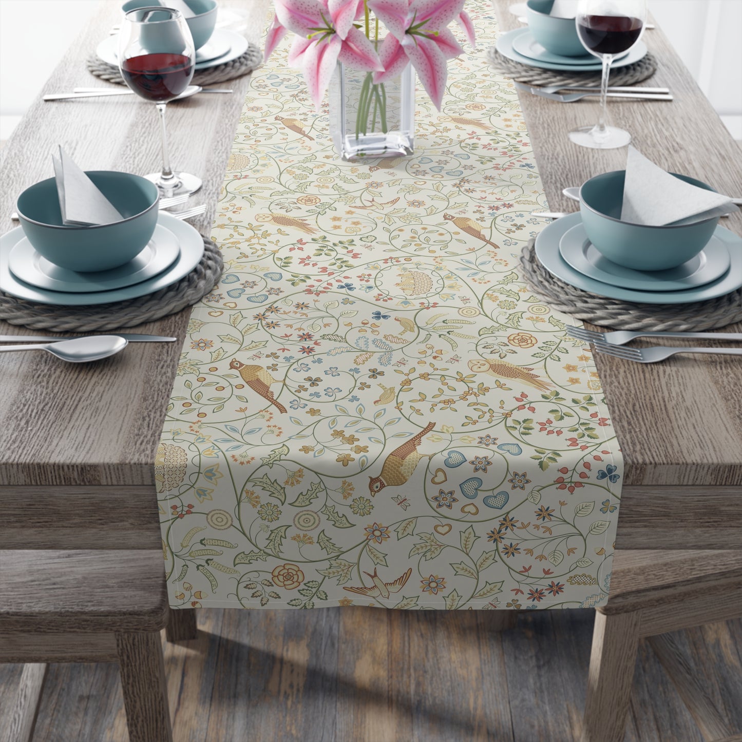 Decorative table runner with floral and bird pattern on a wooden table with place settings.