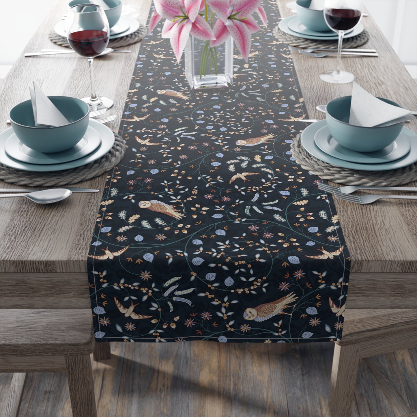 Dining table with a black patterned table runner, blue bowls, and pink flowers.
