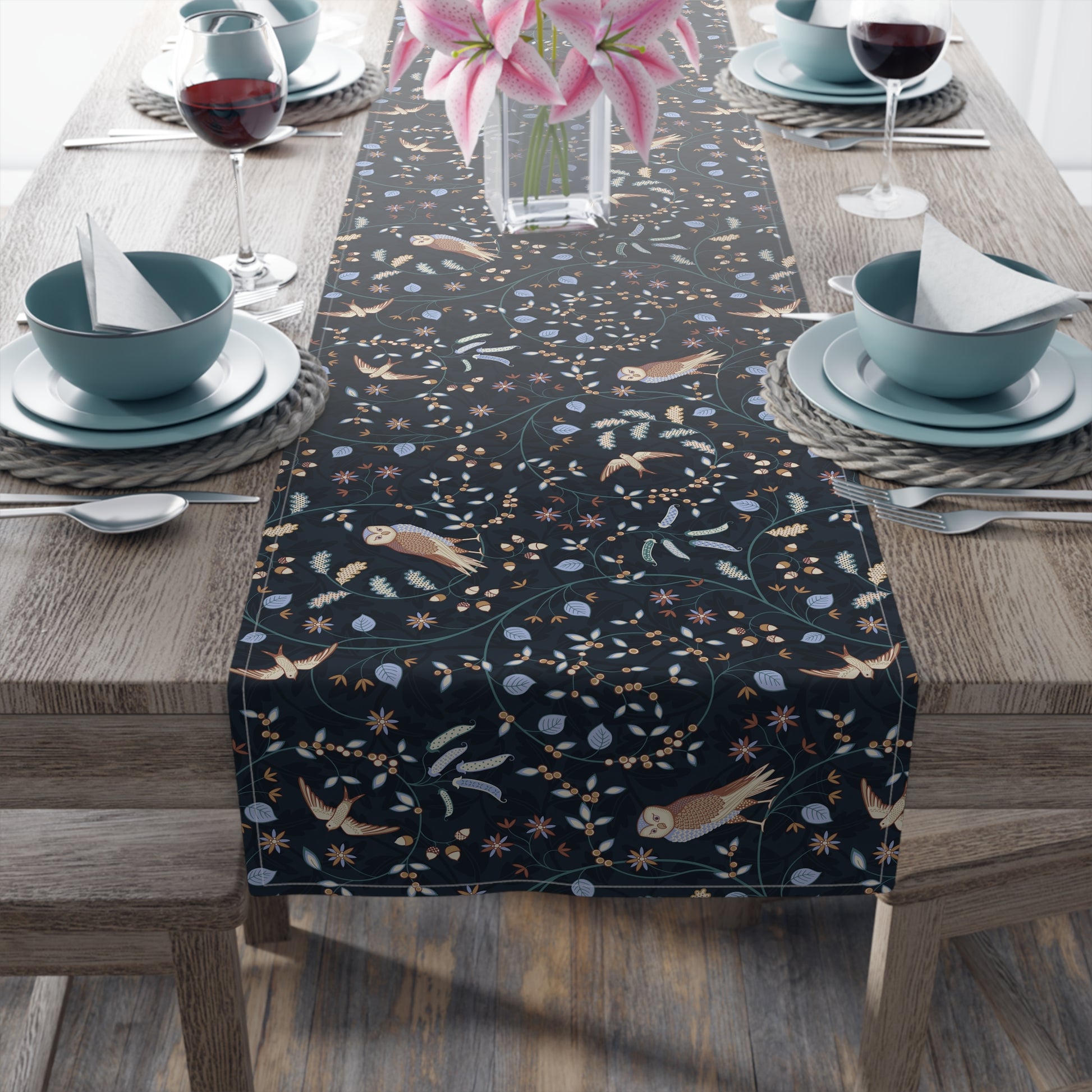 Dining table with a black patterned table runner, blue bowls, and pink flowers.