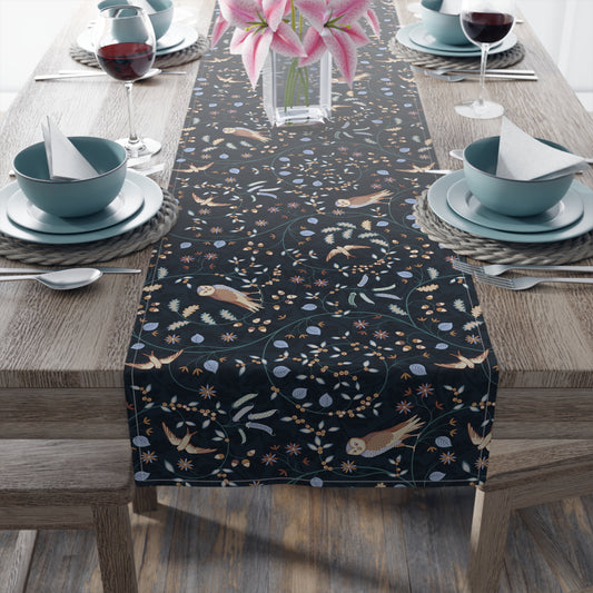Dining table with a black patterned table runner, blue bowls, and pink flowers.