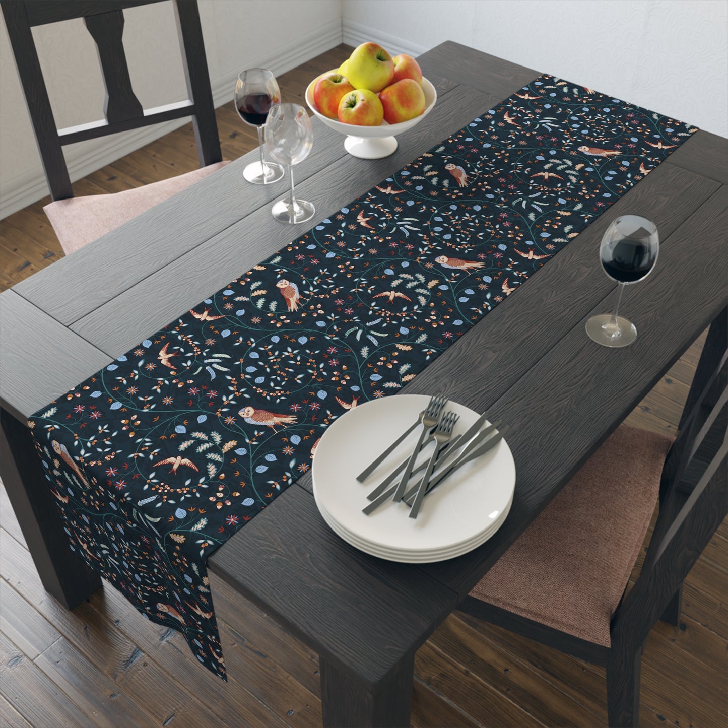 Dining table with a patterned table runner, plates, forks, and glasses.