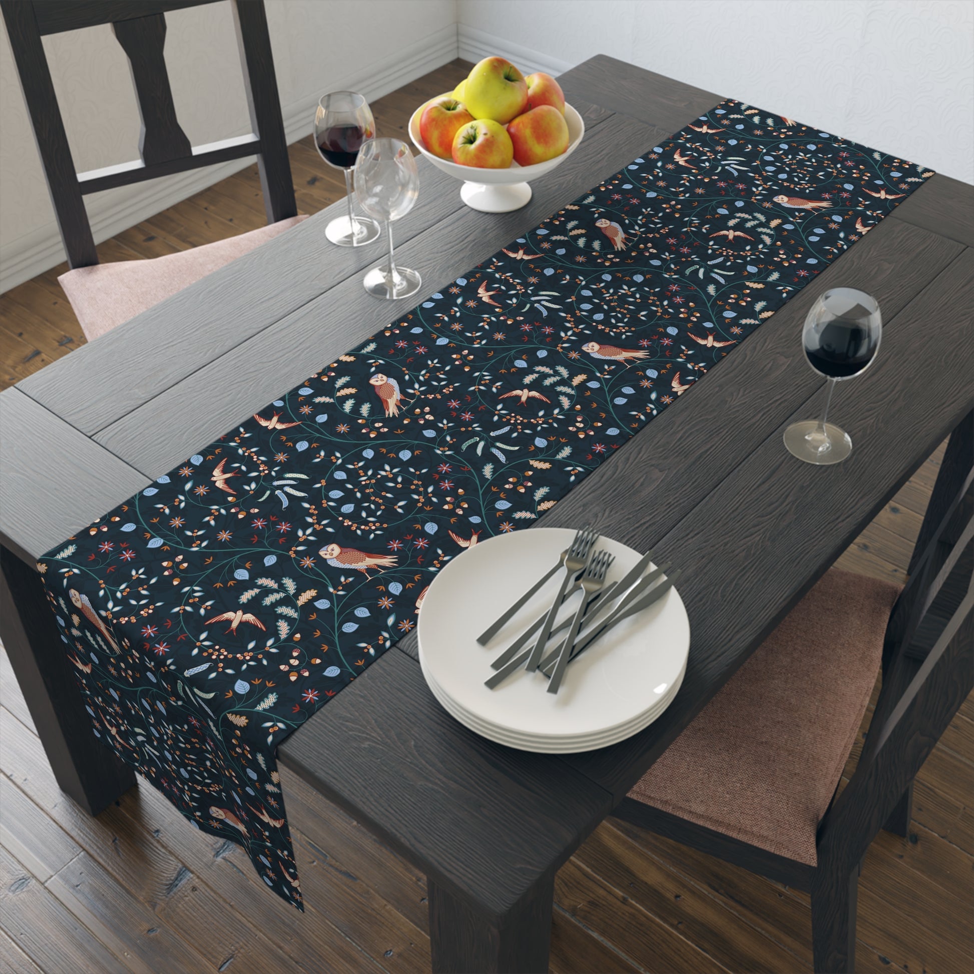 Dining table with a patterned table runner, plates, forks, and glasses.