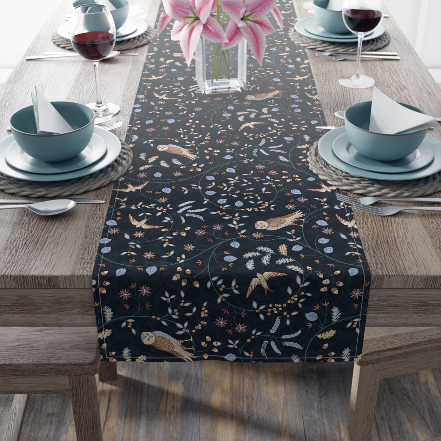 Dining table with a decorative table runner featuring birds and floral patterns on a wooden table.