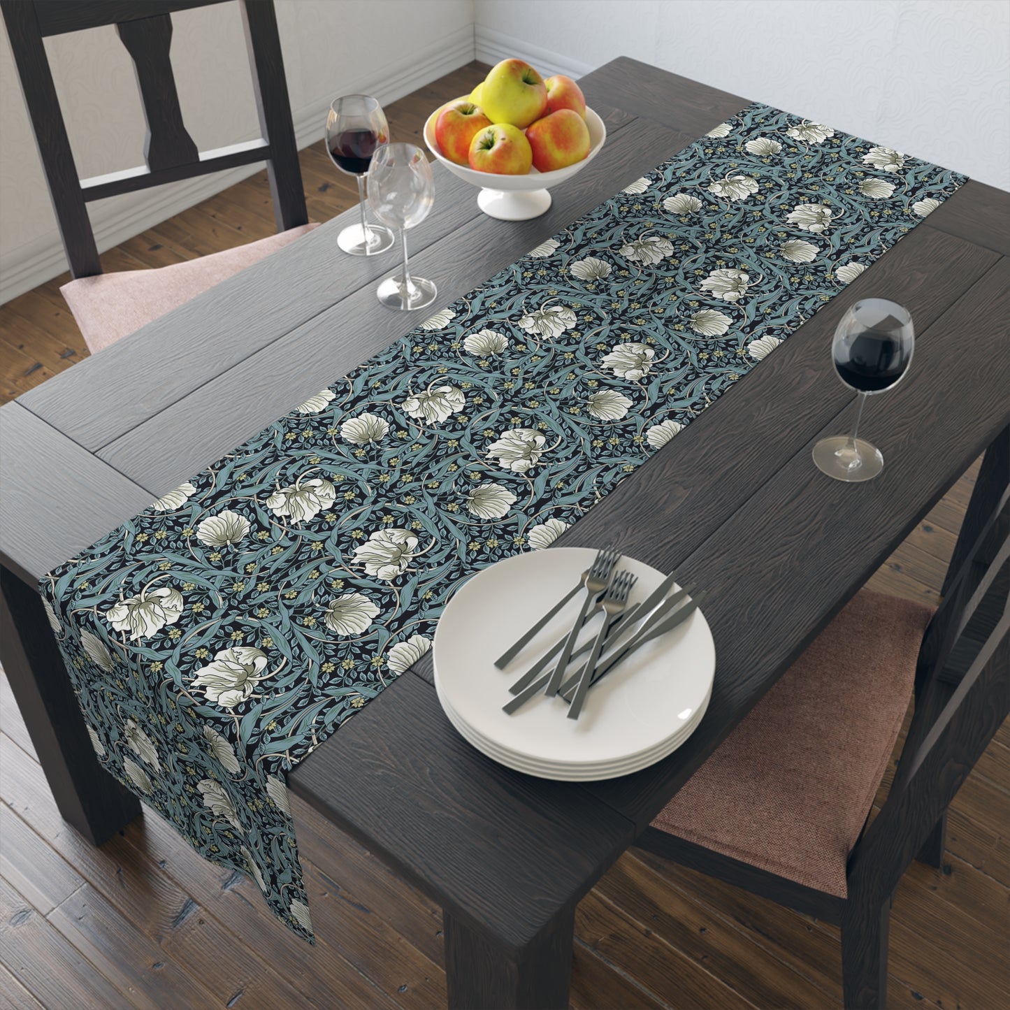 A table runner with a floral William Morris & Co pattern in slate colour laid out on a dining table.