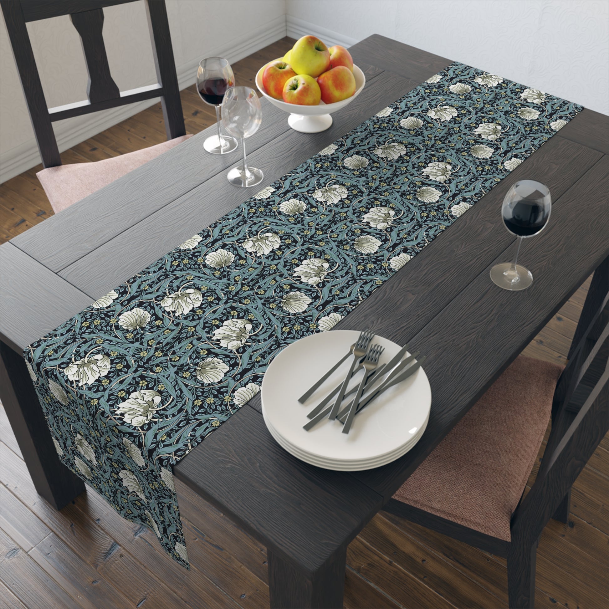 A table runner with a floral William Morris & Co pattern in slate colour laid out on a dining table.