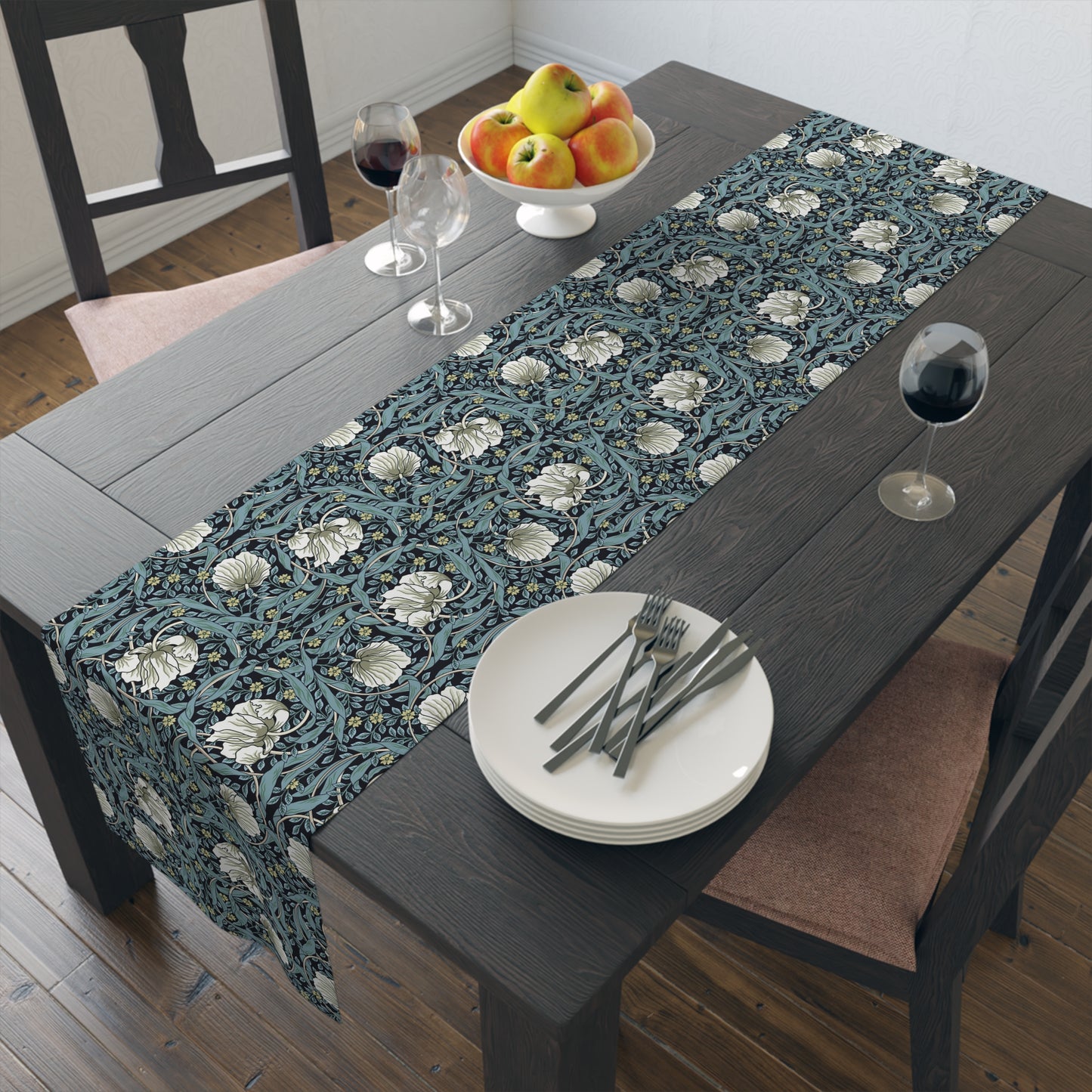 A table runner with a floral William Morris & Co pattern in slate colour laid out on a dining table.