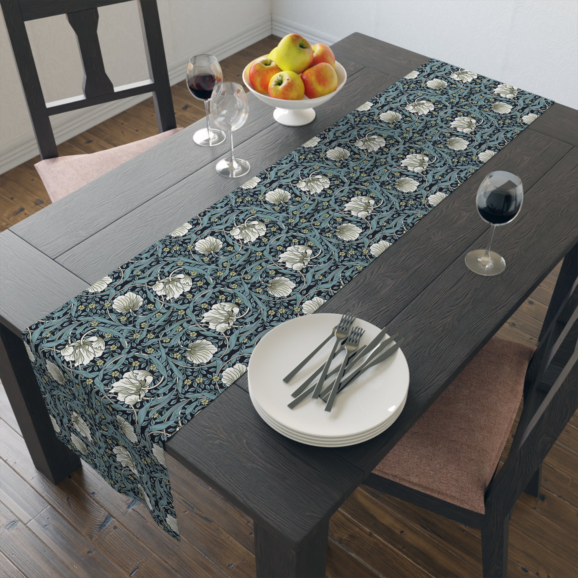 A table runner with a floral William Morris & Co pattern in slate colour laid out on a dining table.