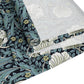 A table runner with a floral William Morris & Co pattern in slate colour laid out on a dining table.