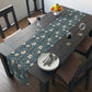 A table runner with a floral William Morris & Co pattern in slate colour laid out on a dining table.