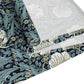 A table runner with a floral William Morris & Co pattern in slate colour laid out on a dining table.