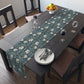 A table runner with a floral William Morris & Co pattern in slate colour laid out on a dining table.