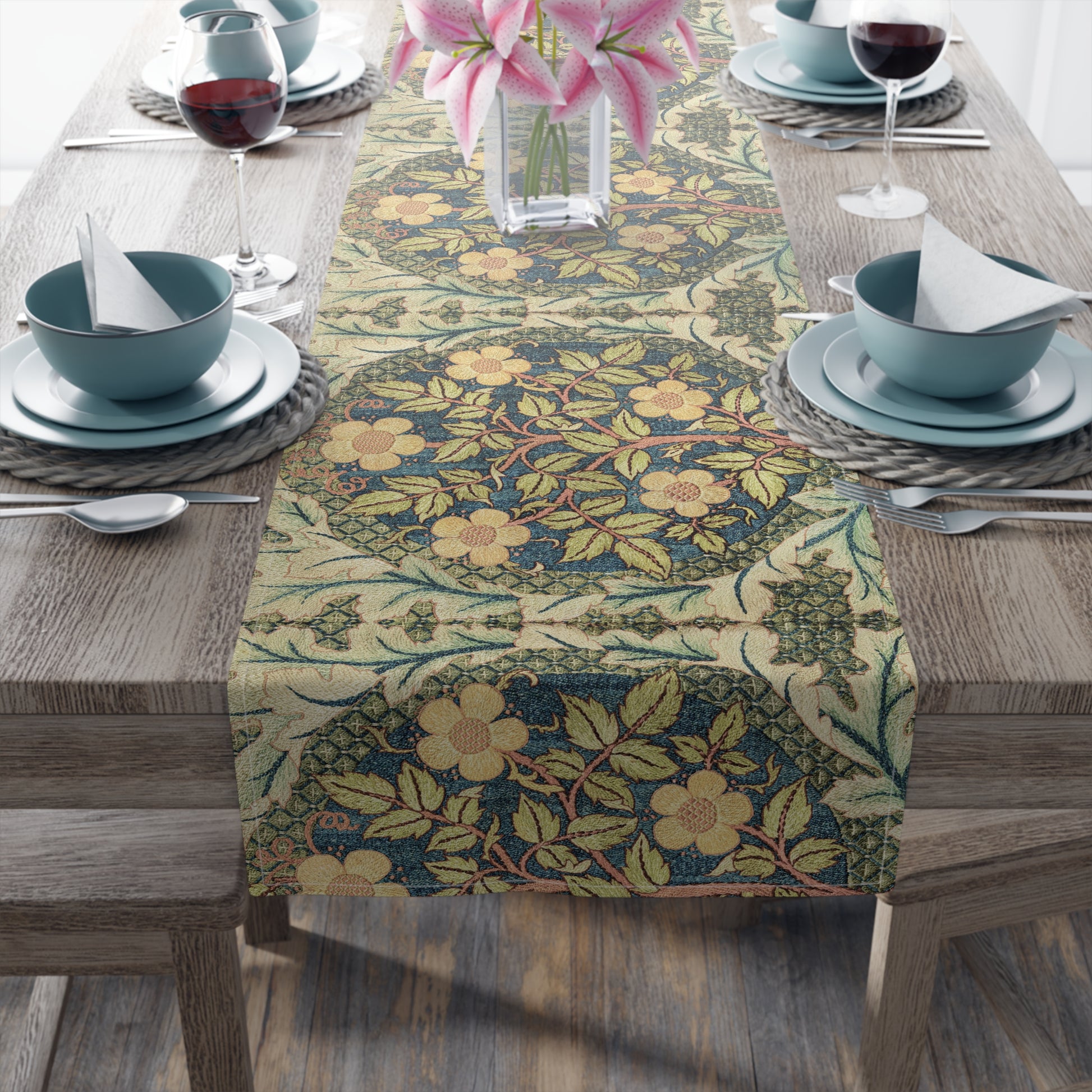 A table runner with a floral pattern inspired by William Morris, displayed on a dining table set with dishes and glasses.