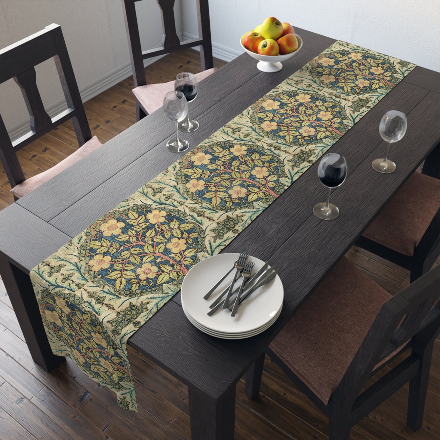 A table runner with a floral pattern inspired by William Morris, displayed on a dining table set with dishes and glasses.