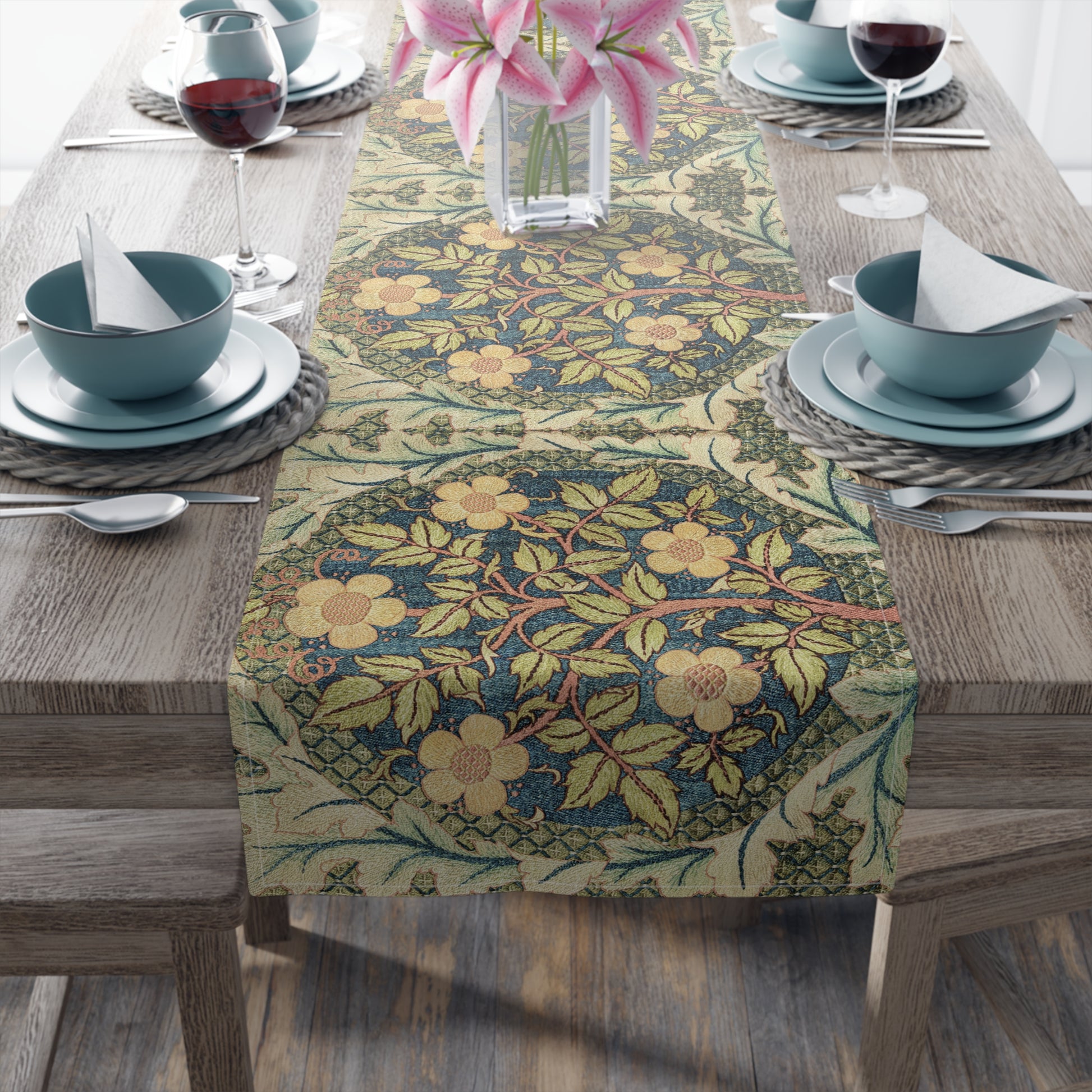 A table runner with a floral pattern inspired by William Morris, displayed on a dining table set with dishes and glasses.