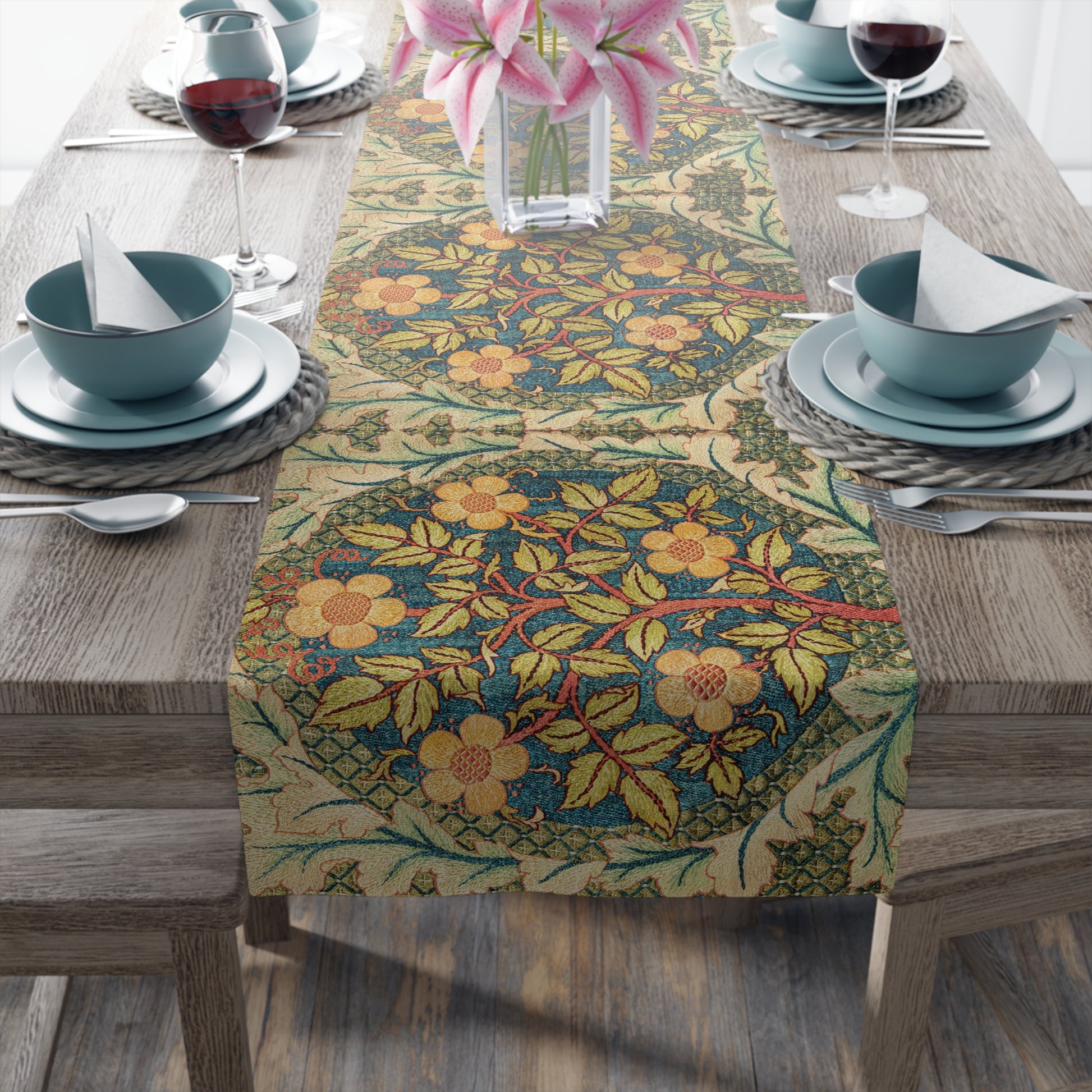 A table runner with a floral pattern inspired by William Morris, displayed on a dining table set with dishes and glasses.