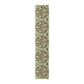 A table runner with a floral pattern inspired by William Morris, displayed on a dining table set with dishes and glasses.