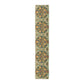 A table runner with a floral pattern inspired by William Morris, displayed on a dining table set with dishes and glasses.