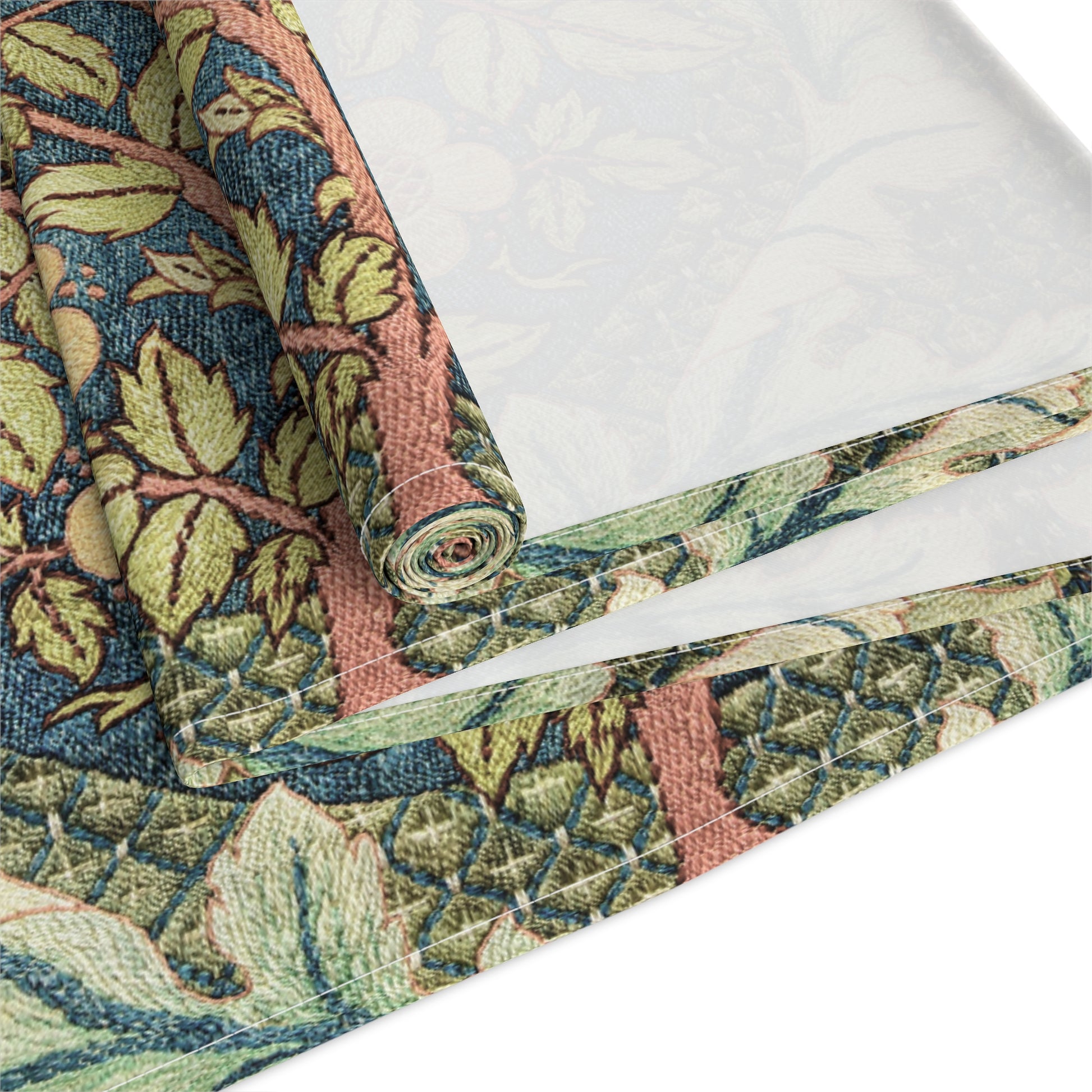 A table runner with a floral pattern inspired by William Morris, displayed on a dining table set with dishes and glasses.