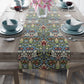 A multicolored floral table runner with geometric patterns displayed on a dining table.