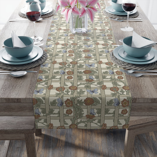 Dining table set with floral-patterned table runner, blue bowls, and pink flowers.