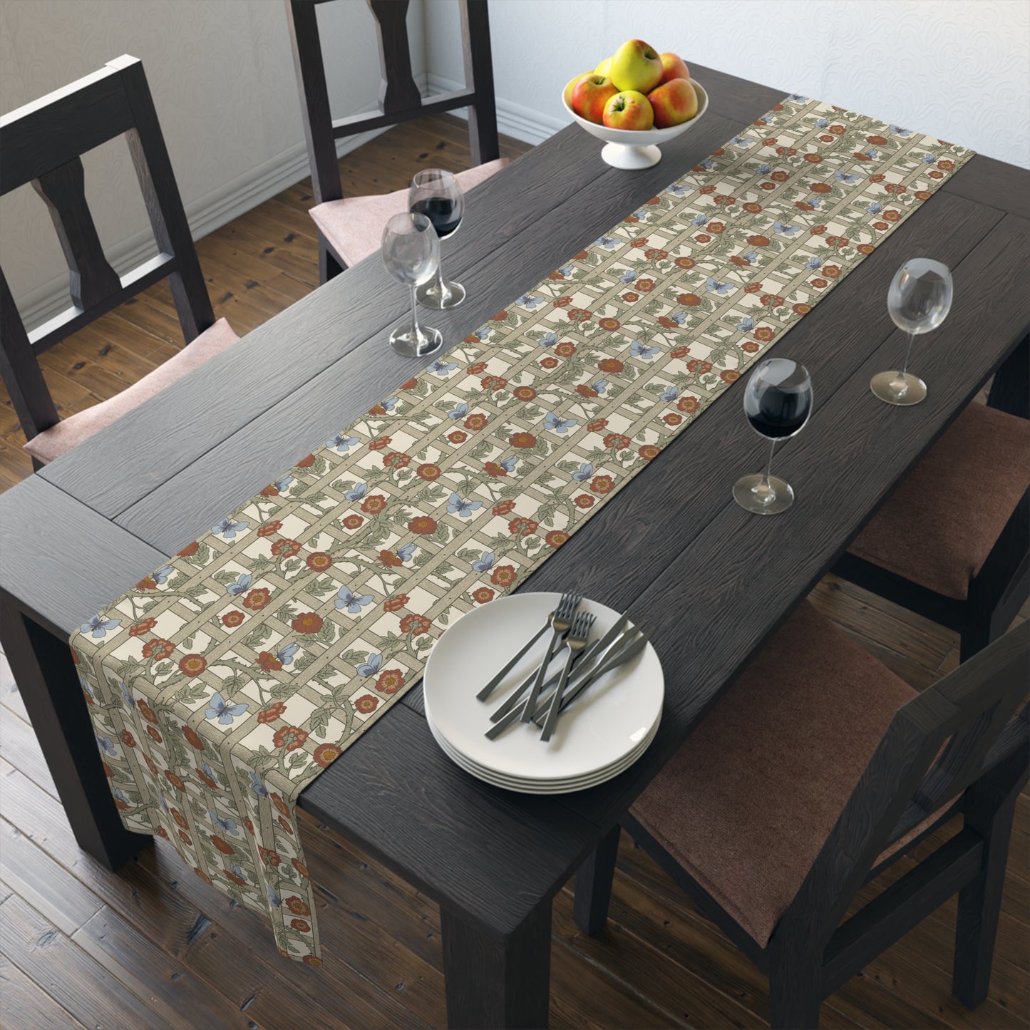 Dining table with a floral patterned table runner, plates, and glasses.