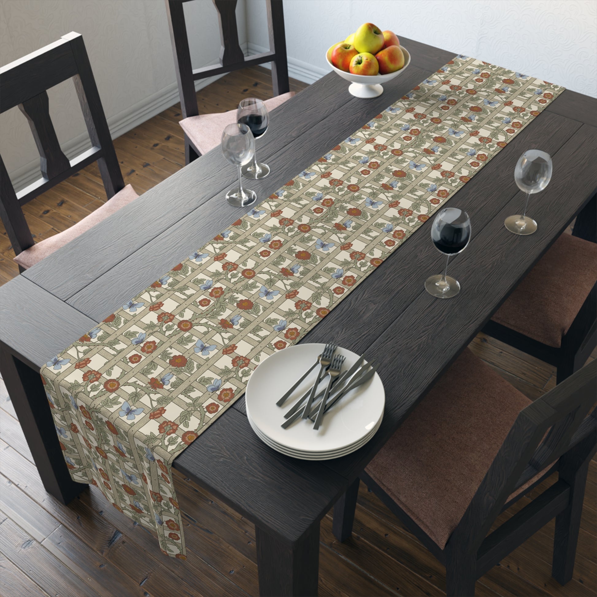 Dining table with a floral patterned table runner, plates, and glasses.