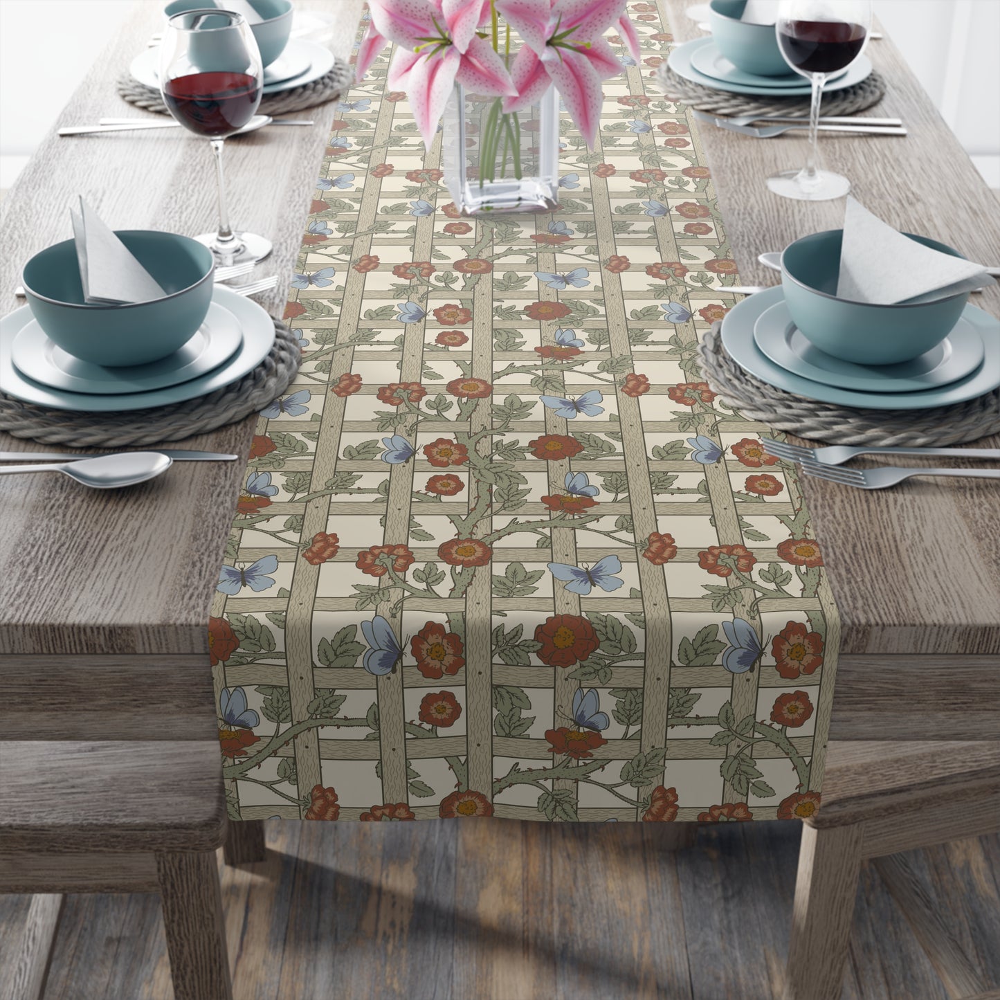 Table setting with a floral table runner on a wooden table.