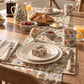 A breakfast table setting featuring a matching floral placemat, ceramic mug, pitcher, and bowls of food on a wooden dining table.