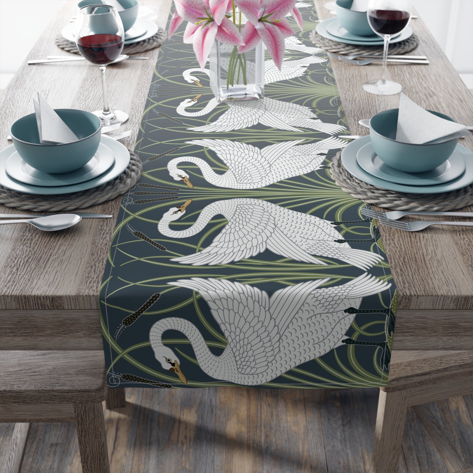 Table setting with a swan patterned table runner on a wooden table.