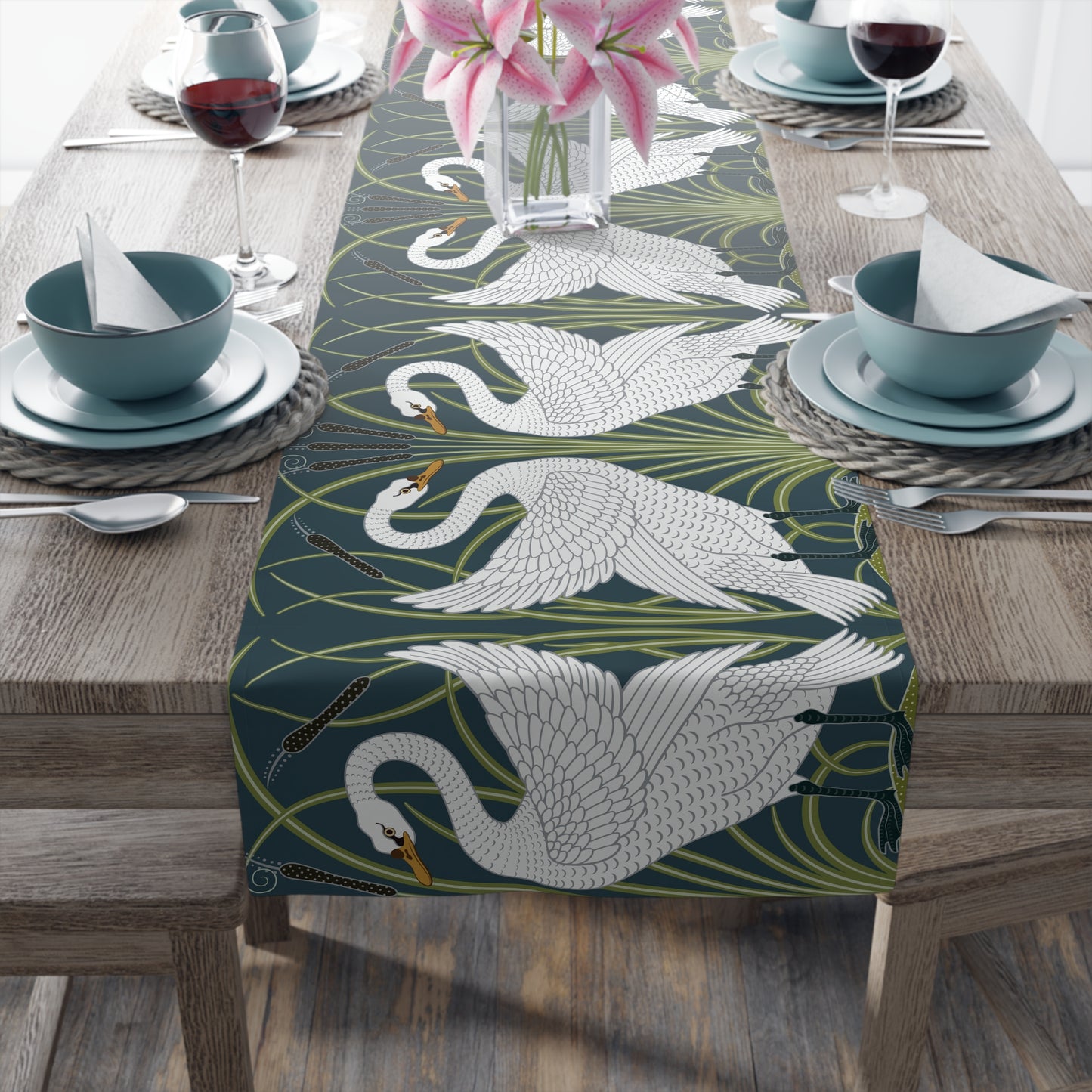 Table setting with a swan patterned table runner on a wooden table.