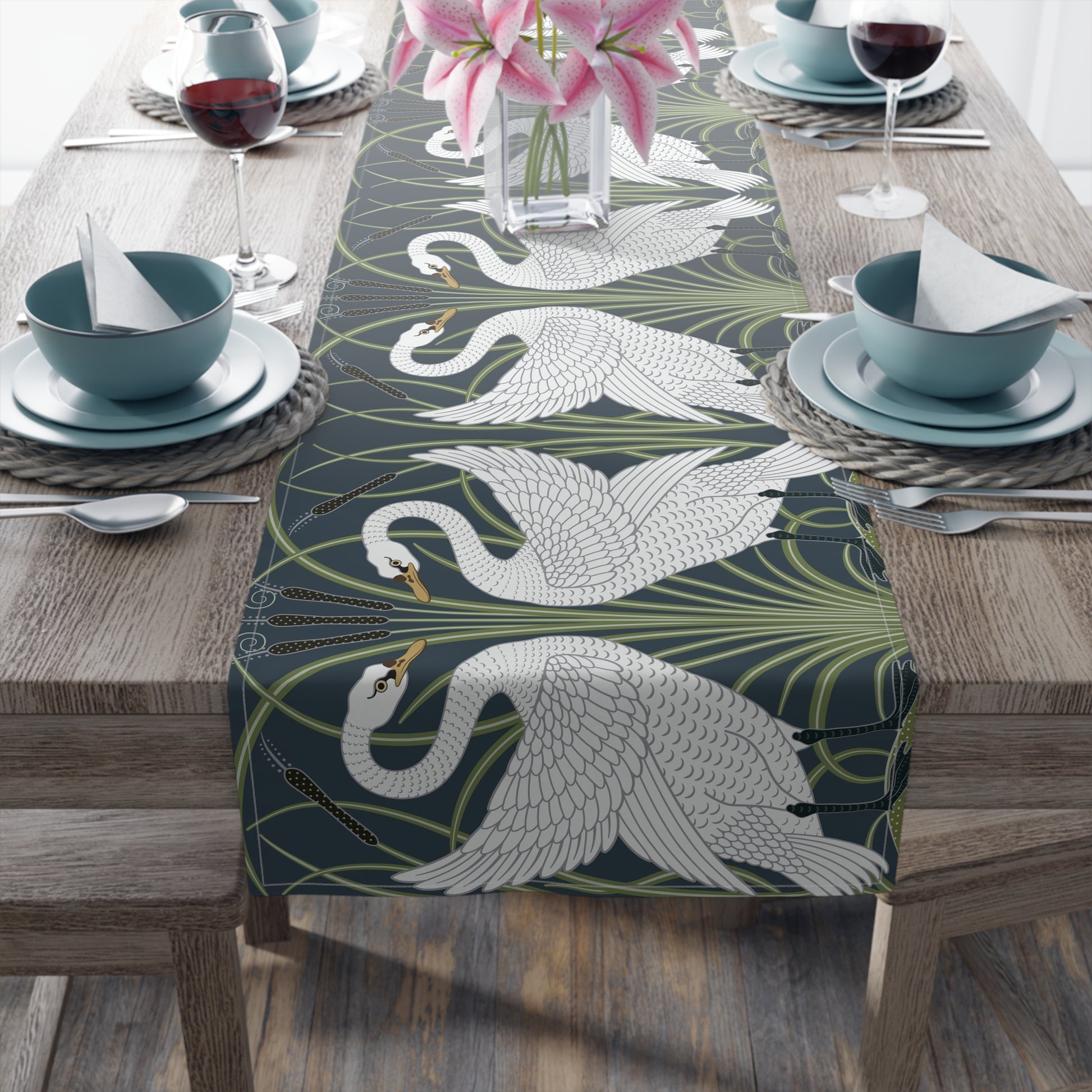 Table setting with a decorative table runner featuring swan designs on a wooden table.