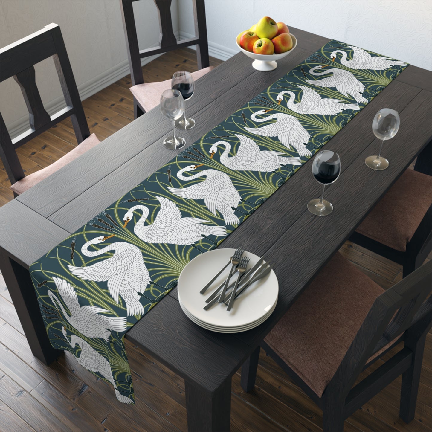 Dining table with swan patterned table runner, plates, and glasses.