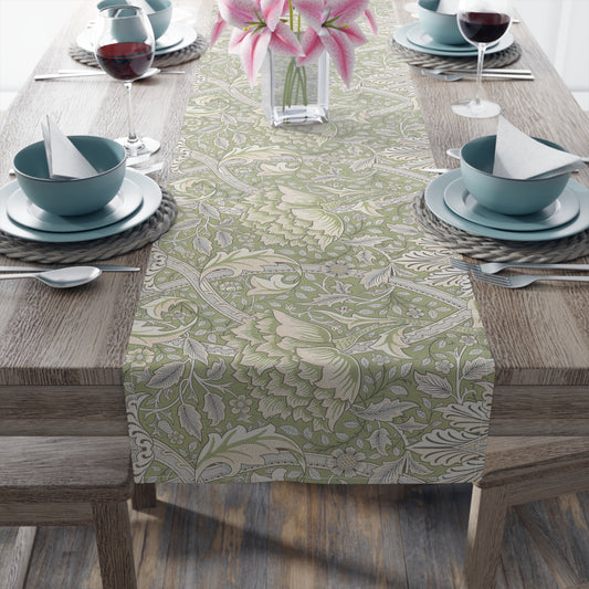 Dining table set with a floral patterned table runner, blue bowls, and pink flowers.