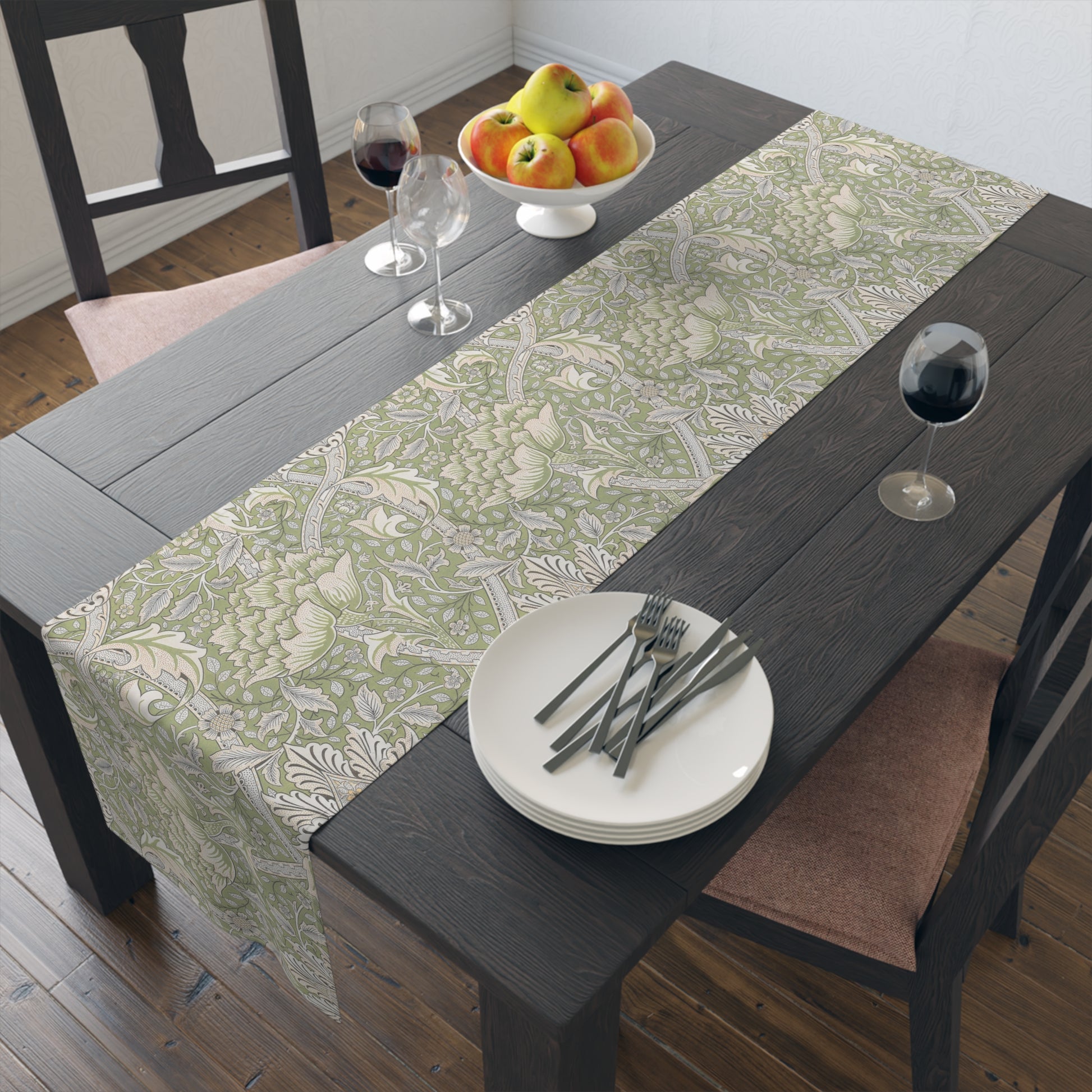 Dining table with a green floral table runner, plates, cutlery, and fruit bowl.