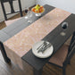 Dining table with a patterned tablecloth, plates, forks, and a fruit bowl.