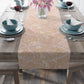 Table setting with a floral table runner on a wooden table.
