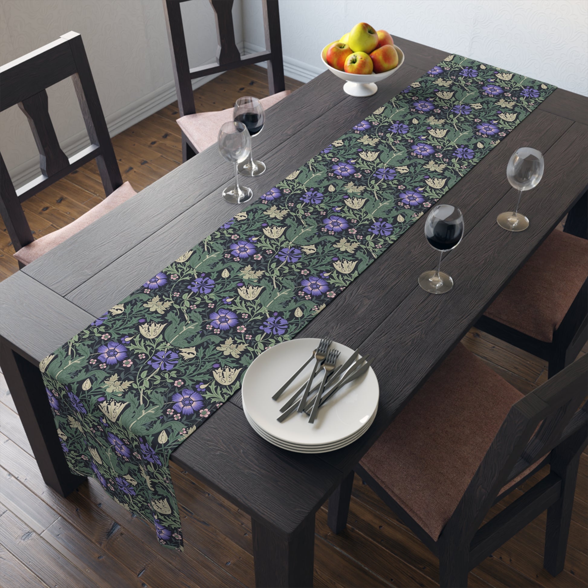 Dining table with a floral table runner, plates, and glasses in a room.