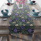 Floral patterned table runner on a wooden table with place settings.